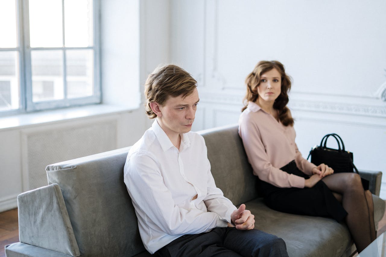 A couple in a session with tense body language on a couch in a bright loft.
